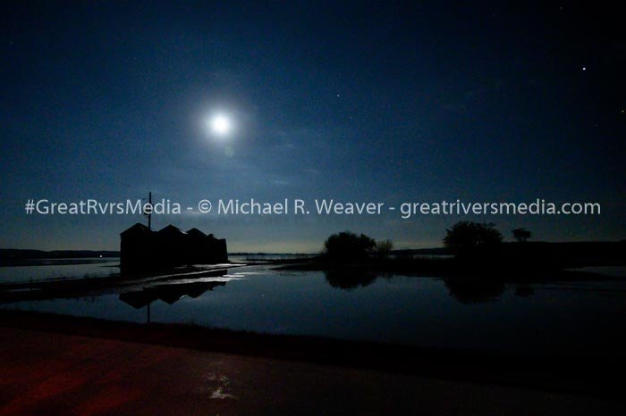 Grain bins that were once mostly submerged make a silhouette under an almost full moon on August 13, 2019.