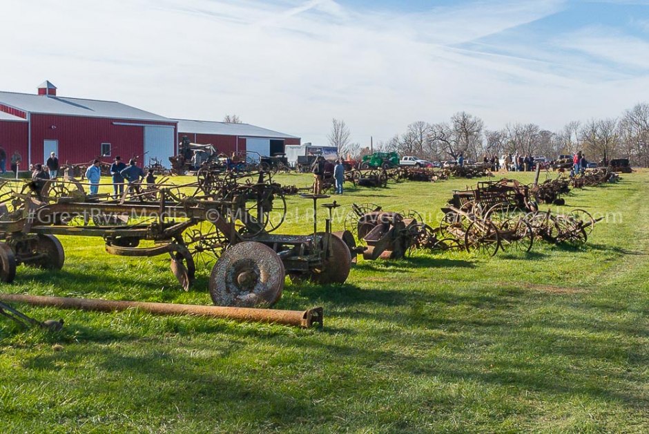 Antique farm equipment in rows waiting to be auctioned.